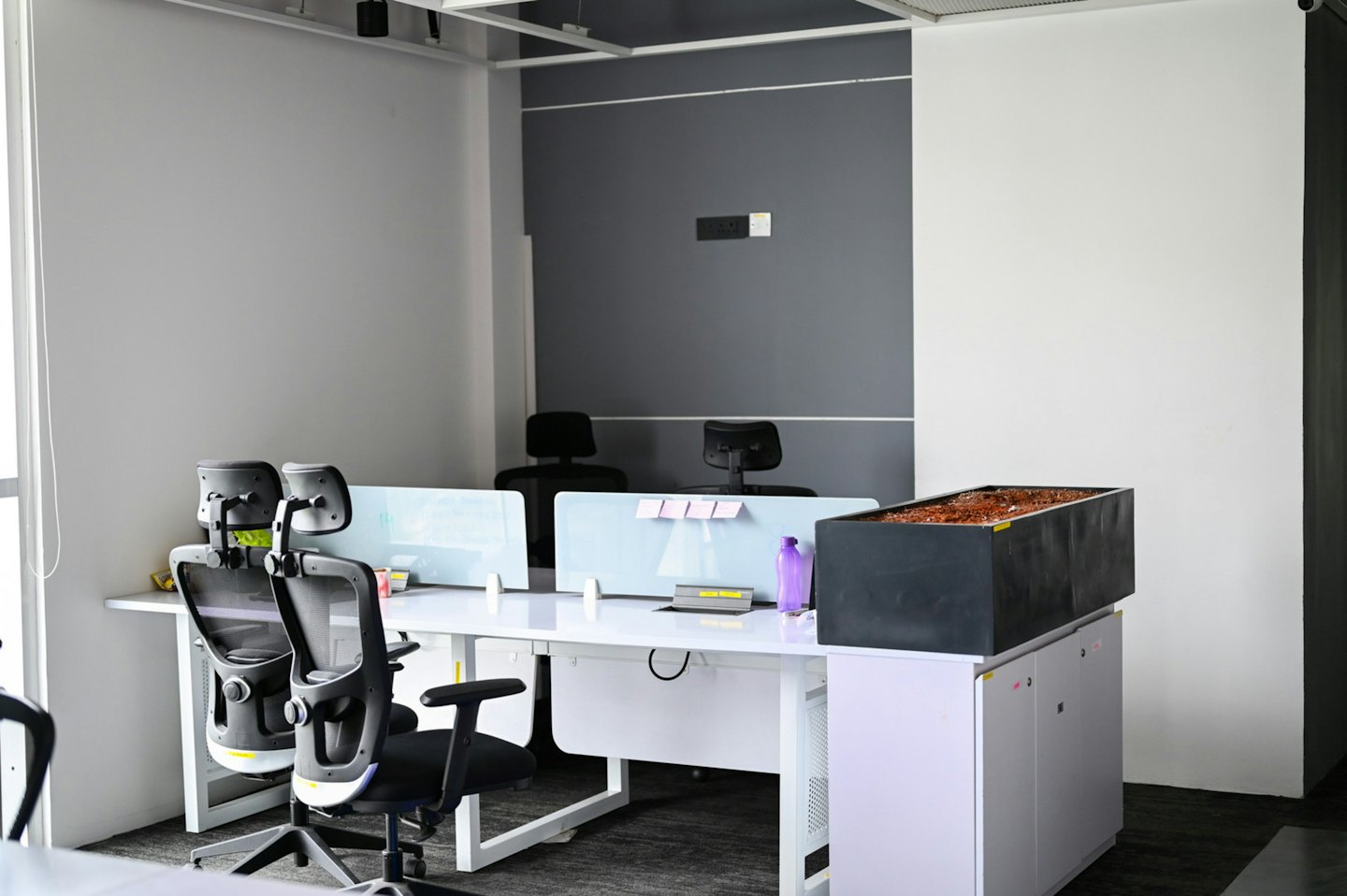 Oficina moderna con escritorios blancos y sillas ergonómicas.